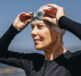 A woman at a beach in a wet suit and swim cap, putting her goggles on ready for a triathlon. Swim, Bike, Run, Cramp Managing Leg Cramps in Triathlons in NZ