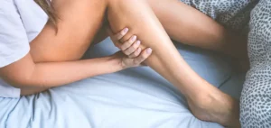Individual in bed holds at their calves after an unrestful night of sleep